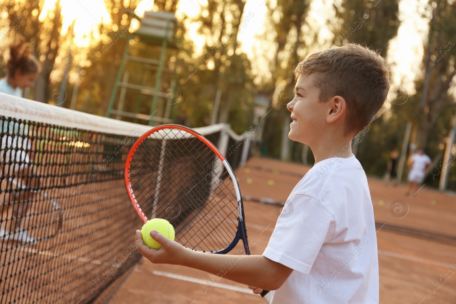 Photo of Cute little boy playing tennis on court outdoors
