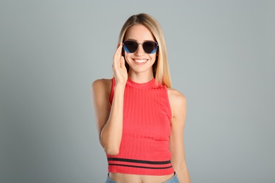 Photo of Beautiful woman in stylish sunglasses on grey background