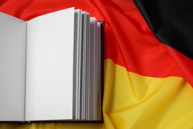 Photo of Learning foreign language. Open book on flag of Germany, top view with space for text
