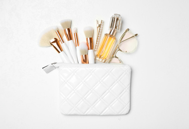 Cosmetic bag with makeup products and beauty accessories on white background, flat lay