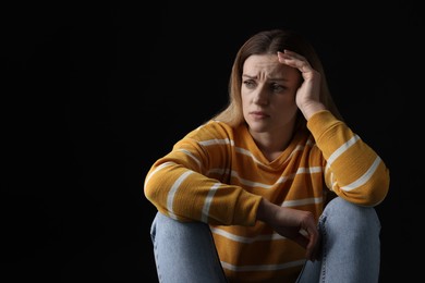 Portrait of sad woman on black background, space for text