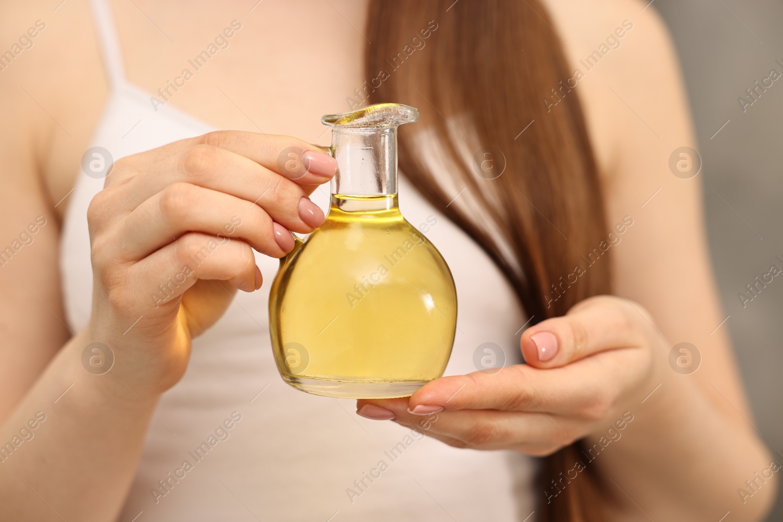 Photo of Natural hair mask. Woman holding jug of oil at home, closeup