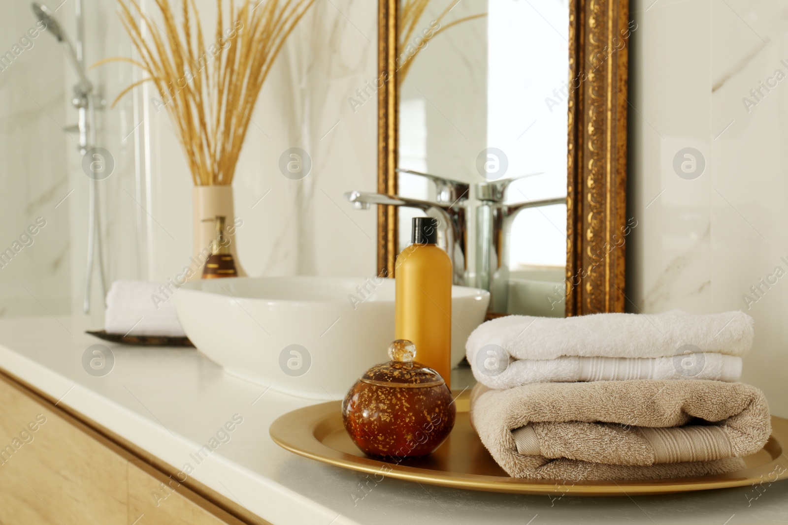 Photo of Toiletries and towels on white countertop near mirror in bathroom