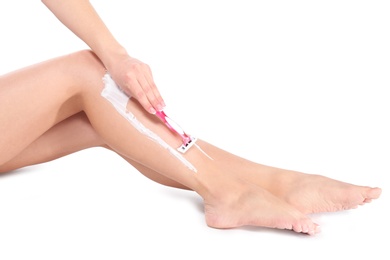 Beautiful young woman shaving leg on white background, closeup view