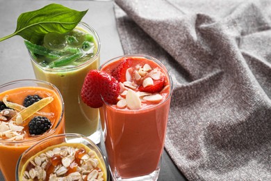 Many different delicious smoothies on grey table. Space for text