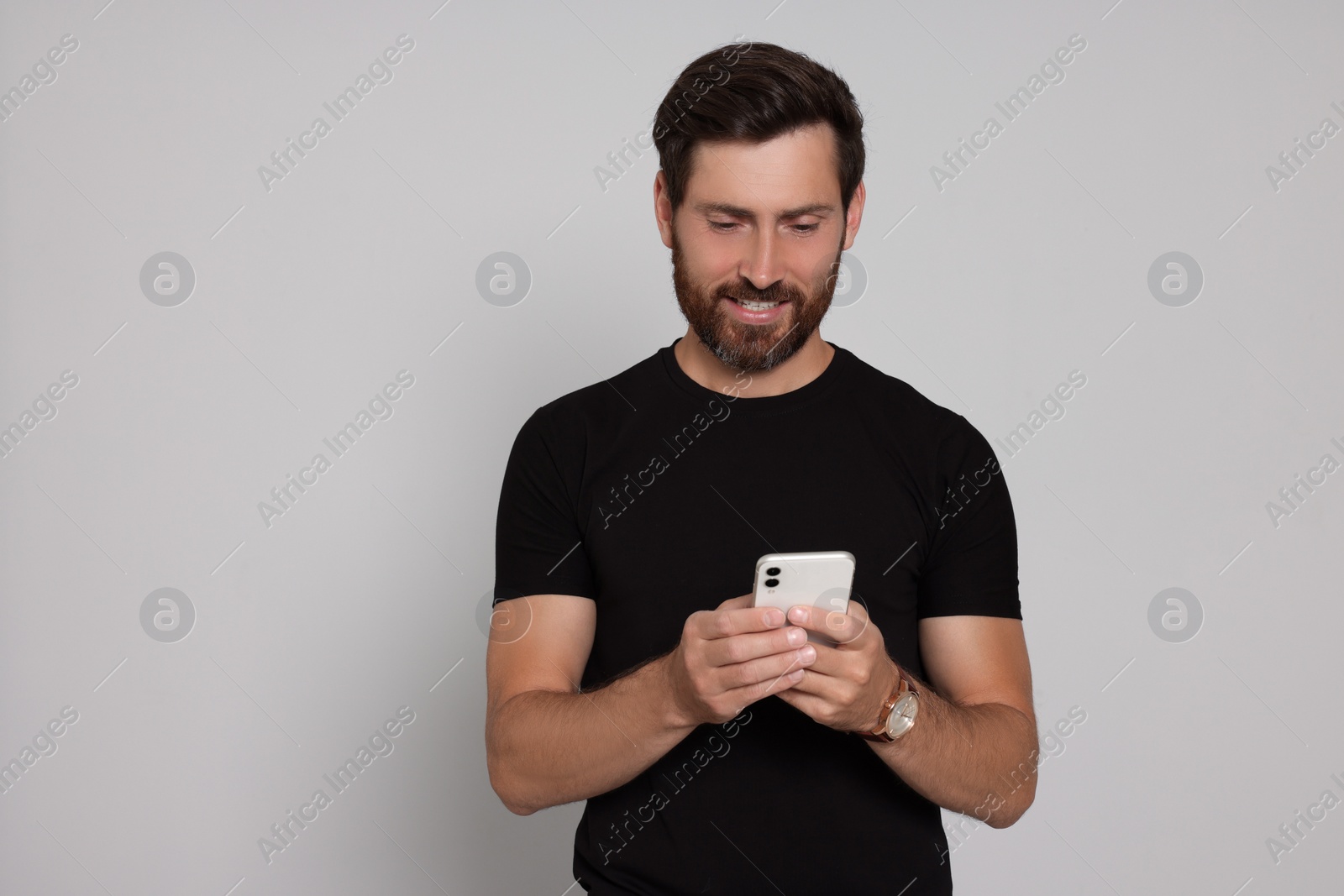 Photo of Happy man with smartphone on light background