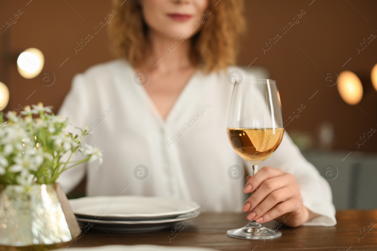 Photo of Woman with glass of wine at table in restaurant