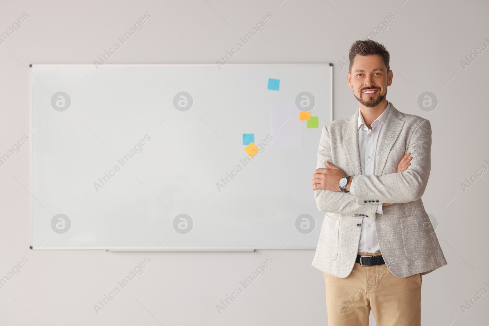 Photo of Happy teacher at whiteboard in classroom. Space for text