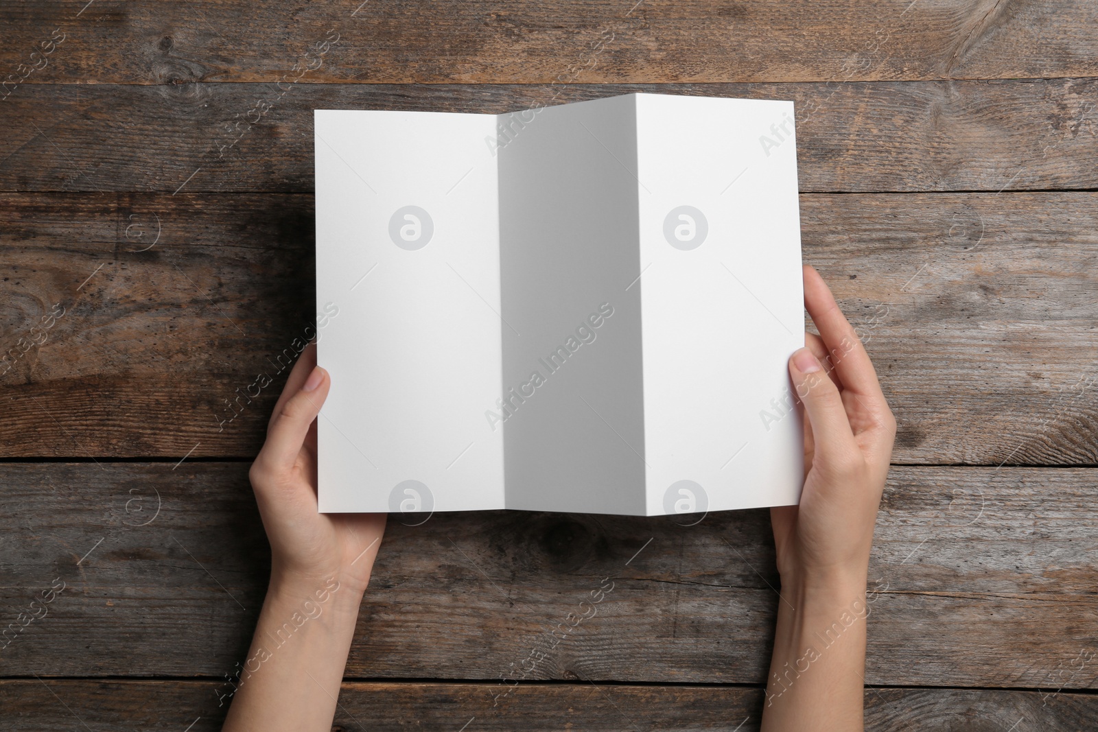 Photo of Woman with blank brochure on wooden background, above view. Mock up for design