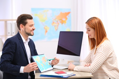 Photo of Male manager consulting client in travel agency