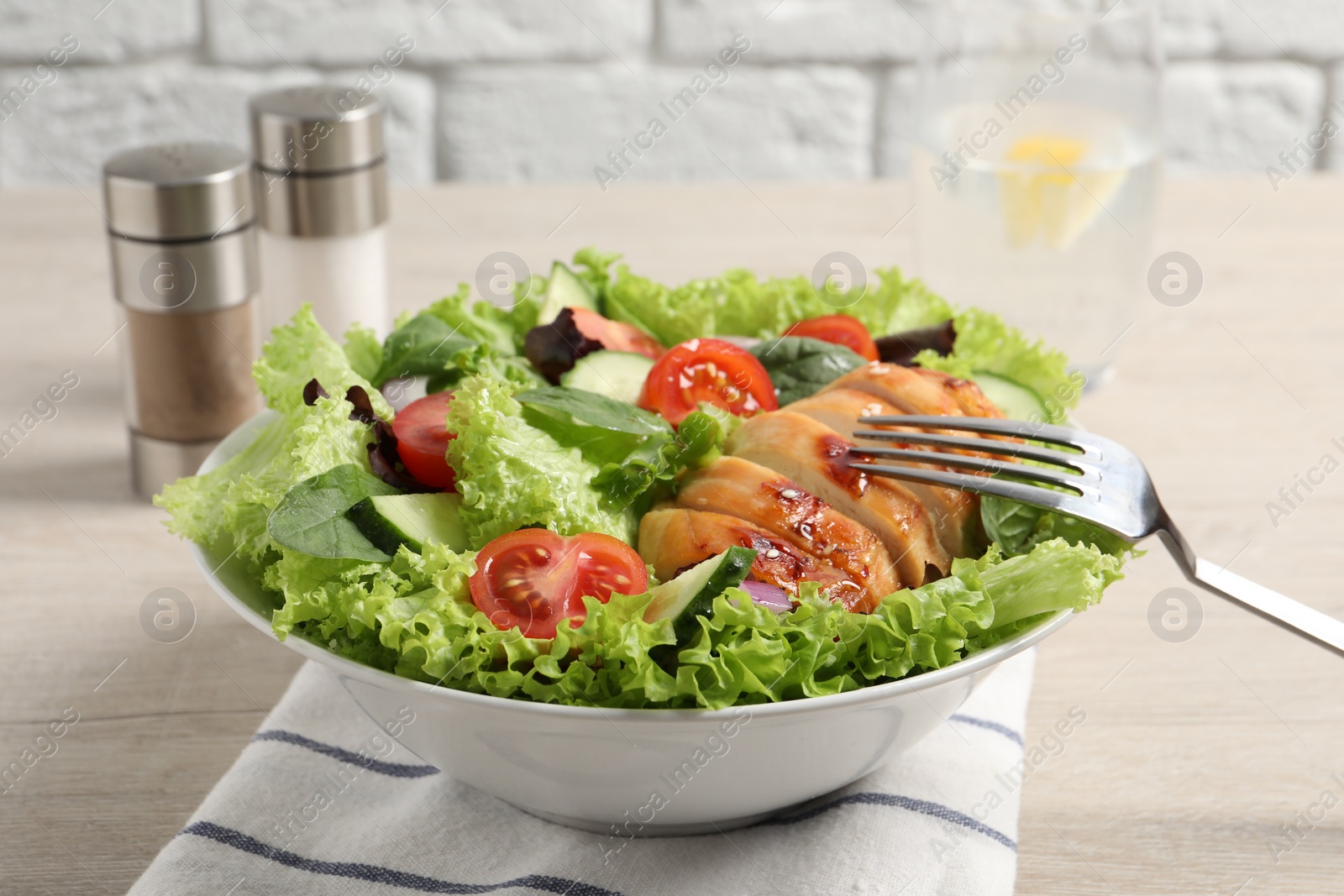 Photo of Eating delicious salad with chicken and vegetables at wooden table, closeup