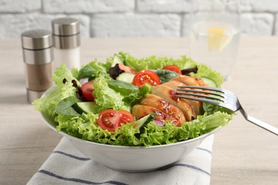 Photo of Eating delicious salad with chicken and vegetables at wooden table, closeup