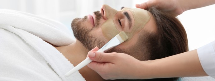 Cosmetologist applying mask on client's face in spa salon. Banner design