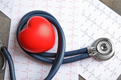 Stethoscope, red heart and cardiograms on table. Cardiology concept