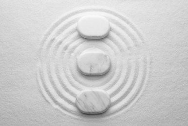 Photo of White stones on sand with pattern, flat lay. Zen, meditation, harmony