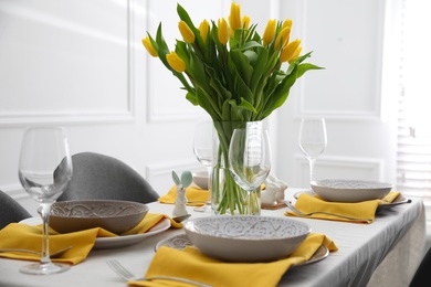 Beautiful Easter table setting with yellow tulips indoors