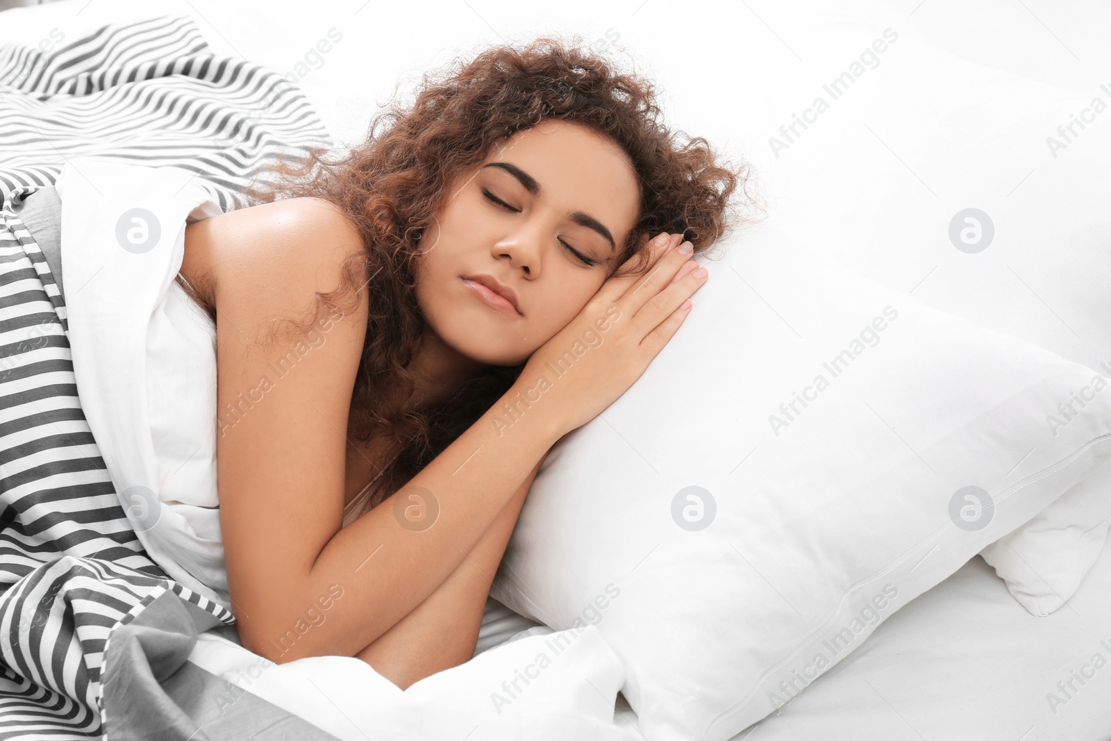 Photo of Young African-American woman sleeping on soft pillow at home. Bedtime