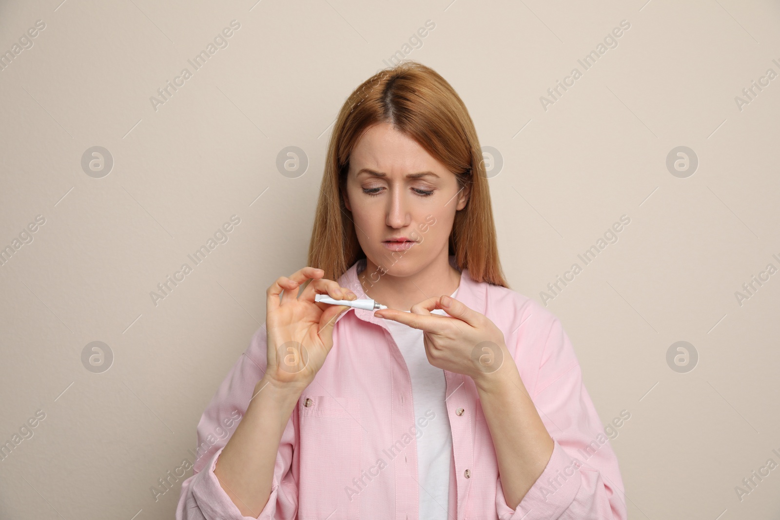 Photo of Woman with herpes applying cream on lips against beige background