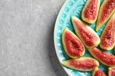 Photo of Plate with fresh ripe fig slices on gray background, top view. Space for text