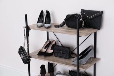 Photo of Shelving unit with stylish shoes and purses near white wall. Element of dressing room interior