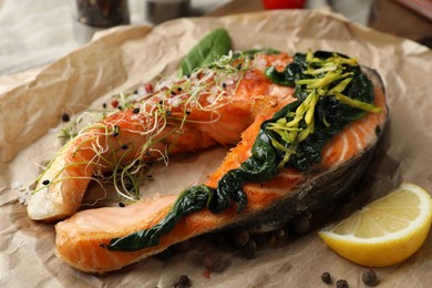 Photo of Tasty salmon with spinach on parchment, closeup