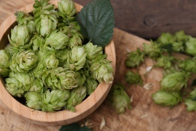 Bowl of fresh green hops on wooden table, closeup
