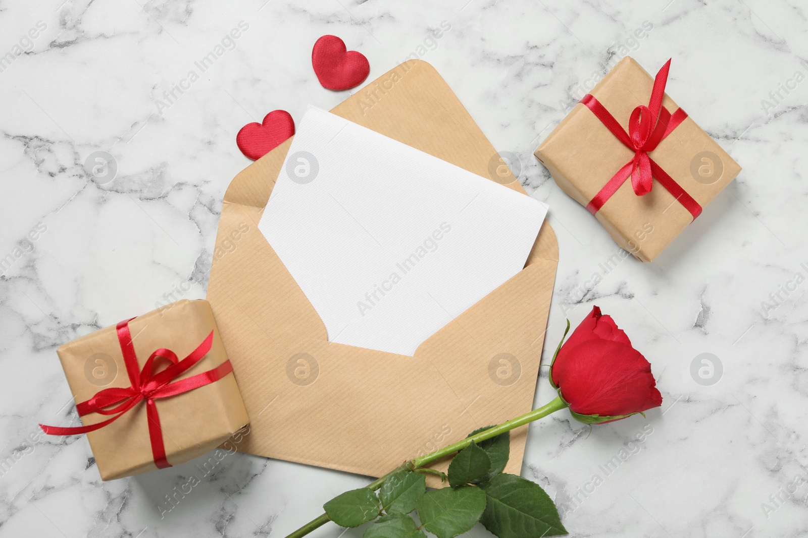 Photo of Flat lay composition with blank greeting card, rose and gifts on white marble table. Valentine's day celebration