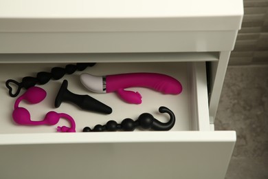 Photo of Vibrator, anal plug, balls and beads in drawer indoors. Sex toys