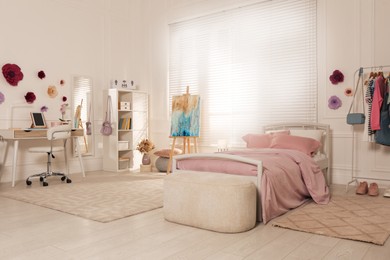 Photo of Stylish teenager's room interior with computer, comfortable bed and painting easel