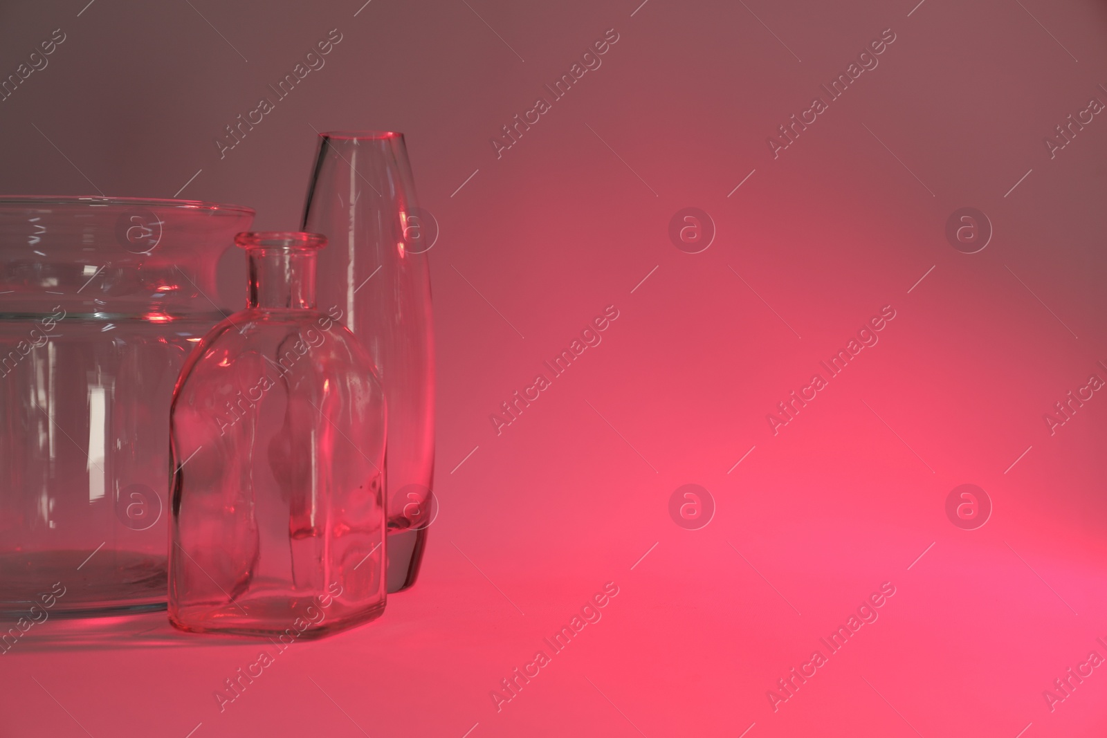 Photo of Different stylish vases on color background, toned in pink. Space for text