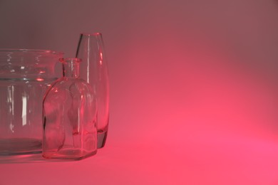 Photo of Different stylish vases on color background, toned in pink. Space for text
