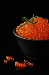 Photo of Delicious red caviar and rosemary on black background, closeup