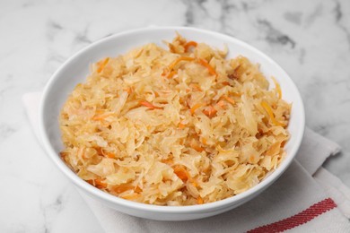 Bowl with tasty sauerkraut on white marble table, closeup