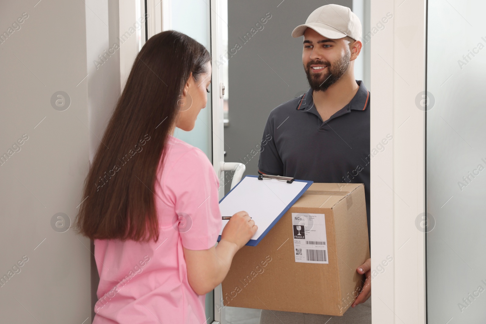 Photo of Woman signing for delivered parcel at home