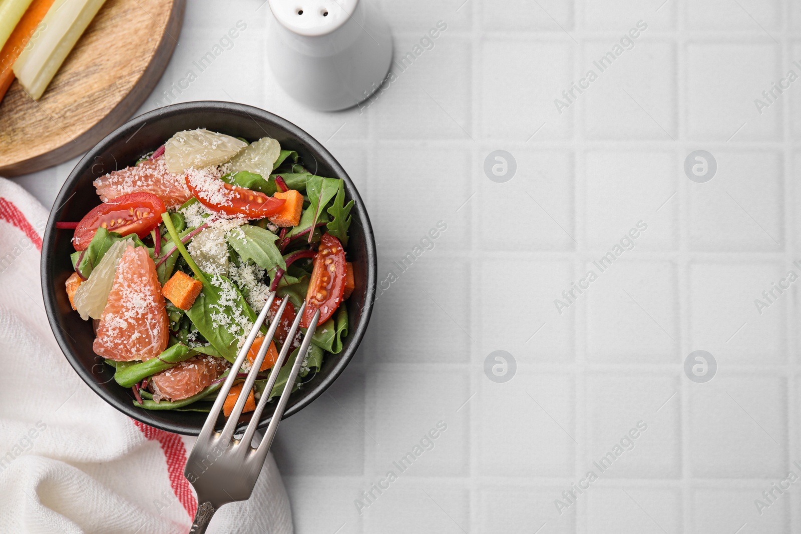 Photo of Delicious salad with pomelo, tomatoes and cheese on white tiled table, flat lay. Space for text