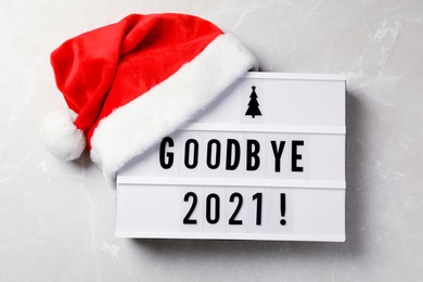 Image of Lightbox with text Bye Bye 2021! and Santa hat on light grey background, flat lay