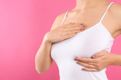 Photo of Woman checking her breast on color background, closeup. Space for text