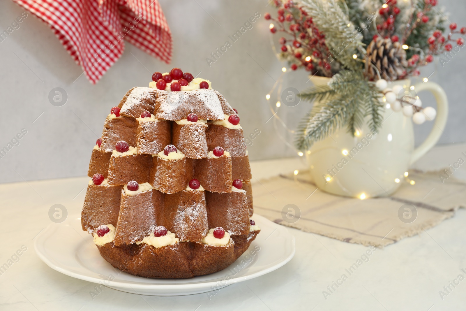 Photo of Delicious Pandoro Christmas tree cake with powdered sugar and berries near festive decor on white table. Space for text