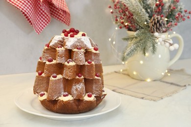 Photo of Delicious Pandoro Christmas tree cake with powdered sugar and berries near festive decor on white table. Space for text