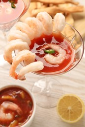 Photo of Tasty shrimp cocktail with sauce in glasses and lemon on light wooden table, closeup