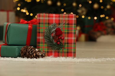 Gift boxes on floor near Christmas tree in room, space for text