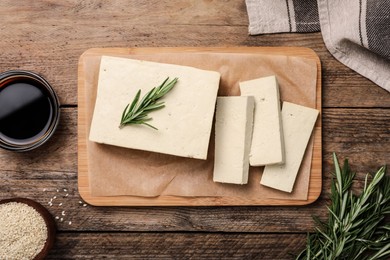 Delicious tofu with rosemary served on wooden table, flat lay