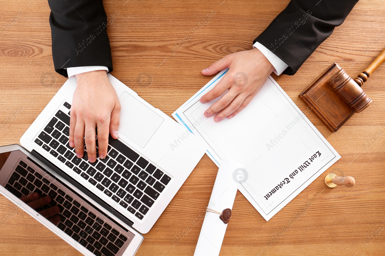 Photo of Male notary working with laptop at wooden table, top view