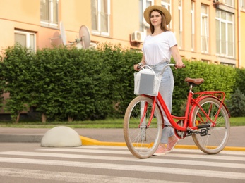 Young pretty woman with bicycle crossing road. Space for text