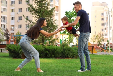 Photo of Happy family playing with adorable little baby in park