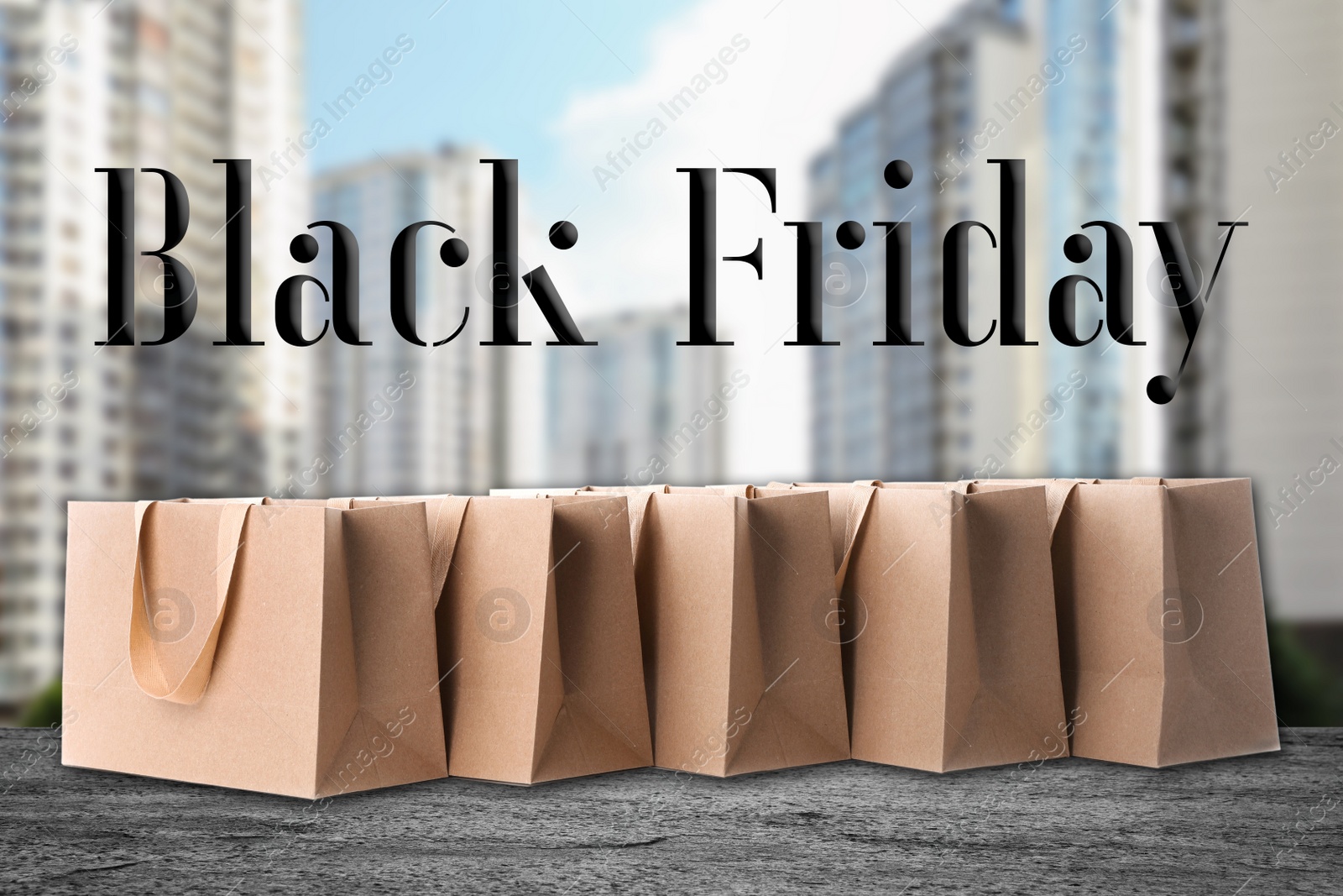 Image of Black Friday. Many shopping bags and blurred cityscape on background