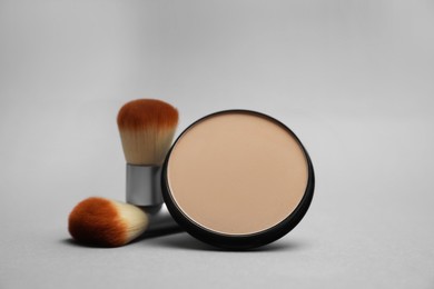 Photo of Open face powder and brushes on light grey background
