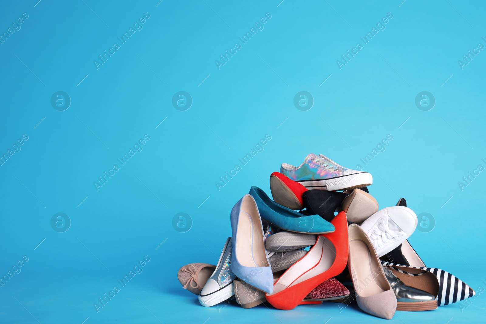 Photo of Heap of different shoes on color background. Space for text