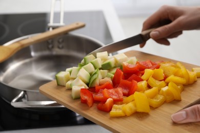 Photo of Woman putting cut vegetables into saute pan in kitchen, closeup