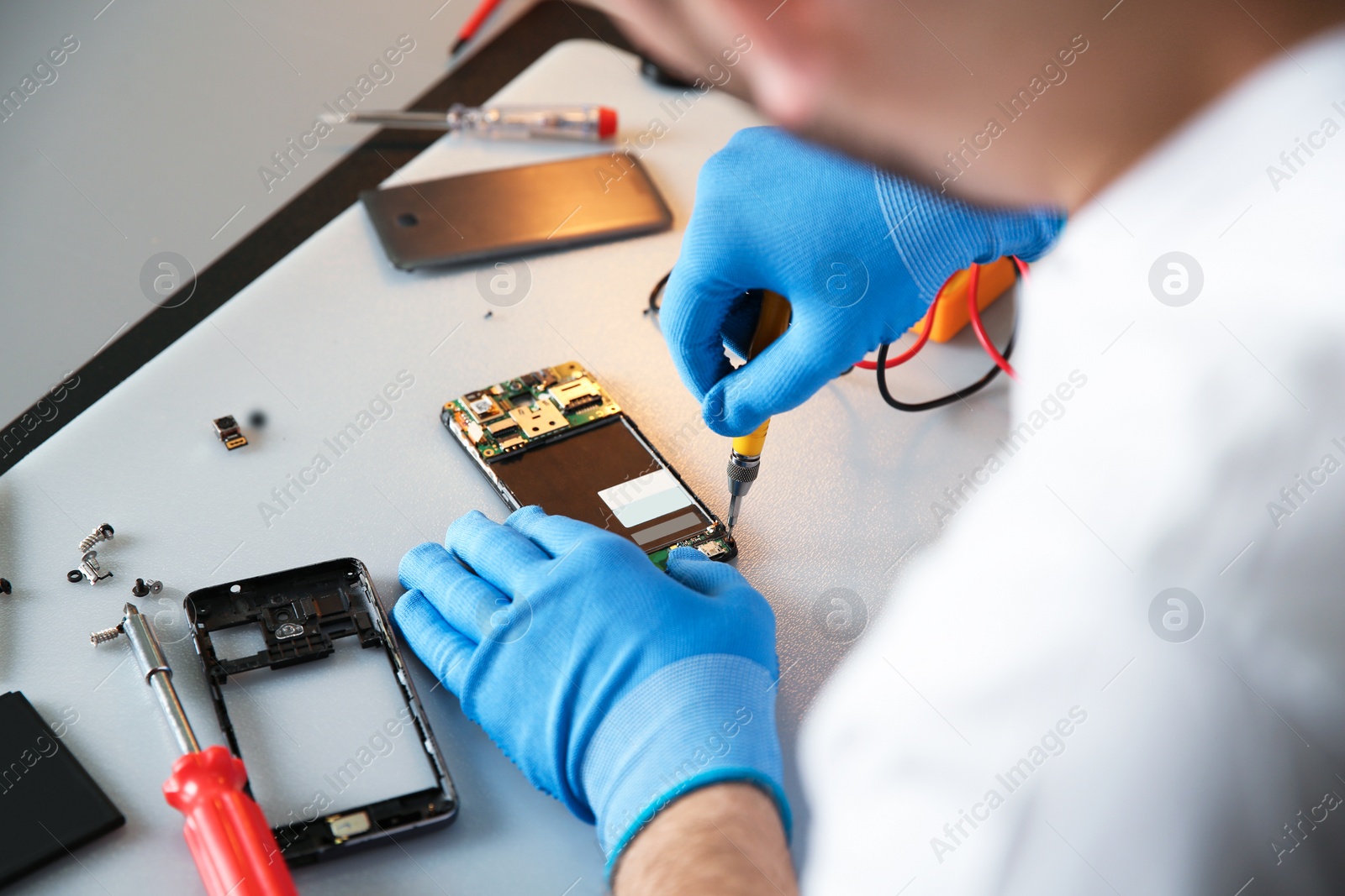 Photo of Technician repairing mobile phone at table, closeup